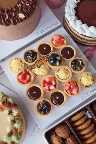 Assorted pastries including tarts and cookies on a branded box with 'Le Berries' branding.