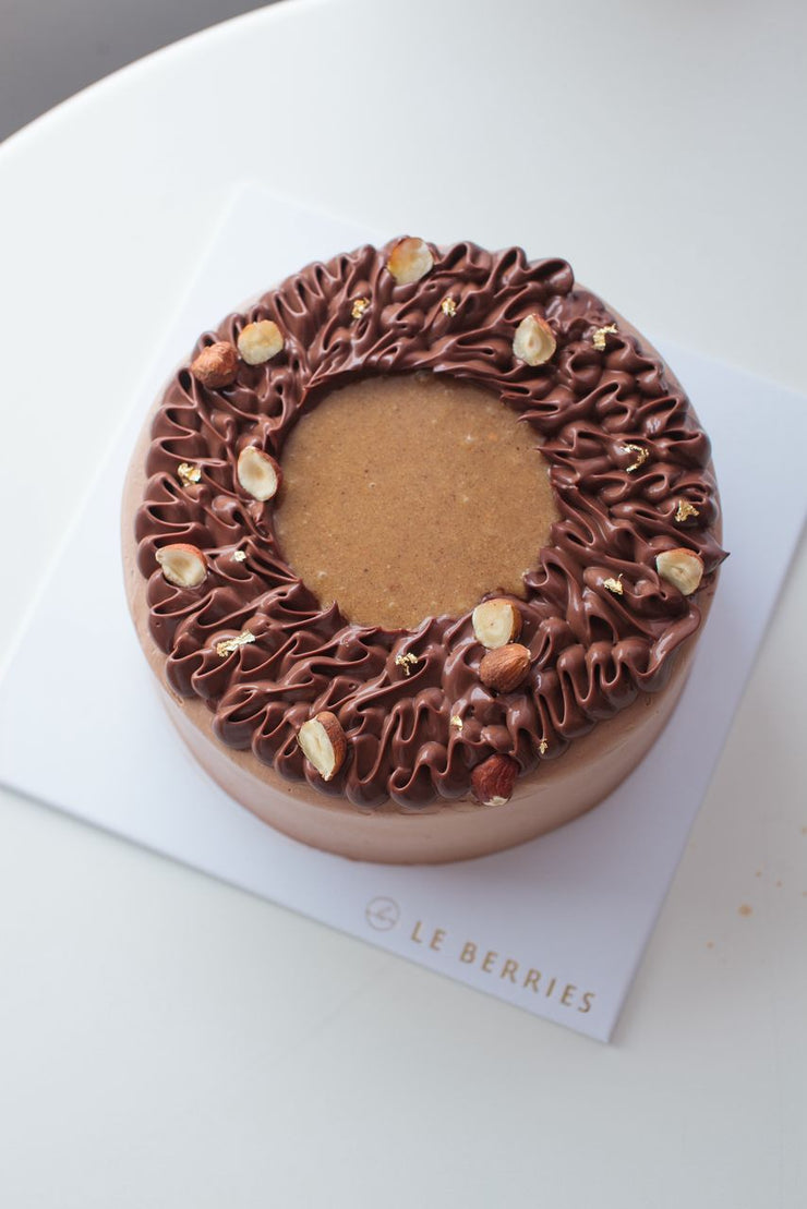 Chocolate Hazelnut cake with nuts on a white surface, branded &